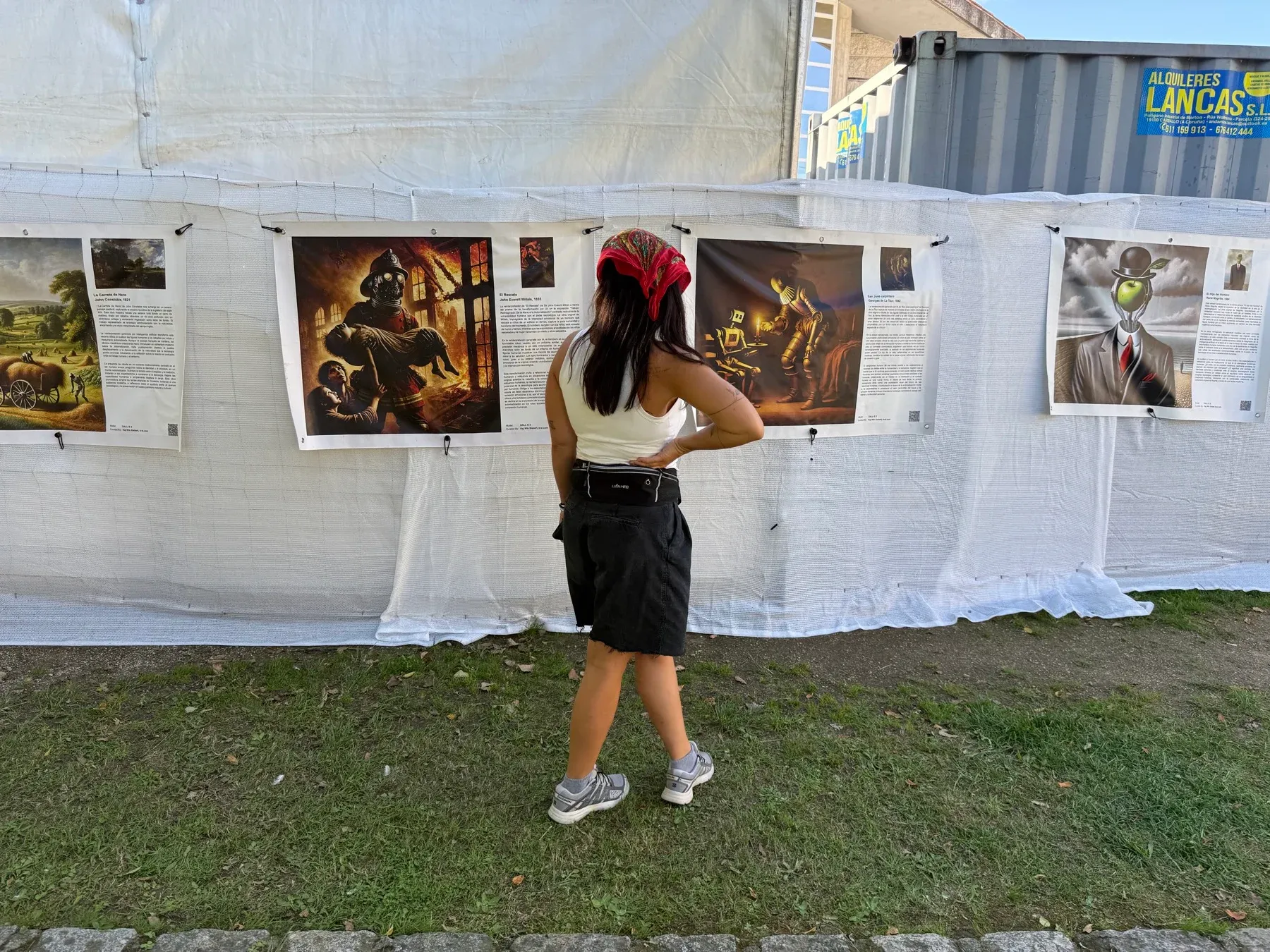 A festival visitor reading the exhibition posters hung along the outside of a white marquee.