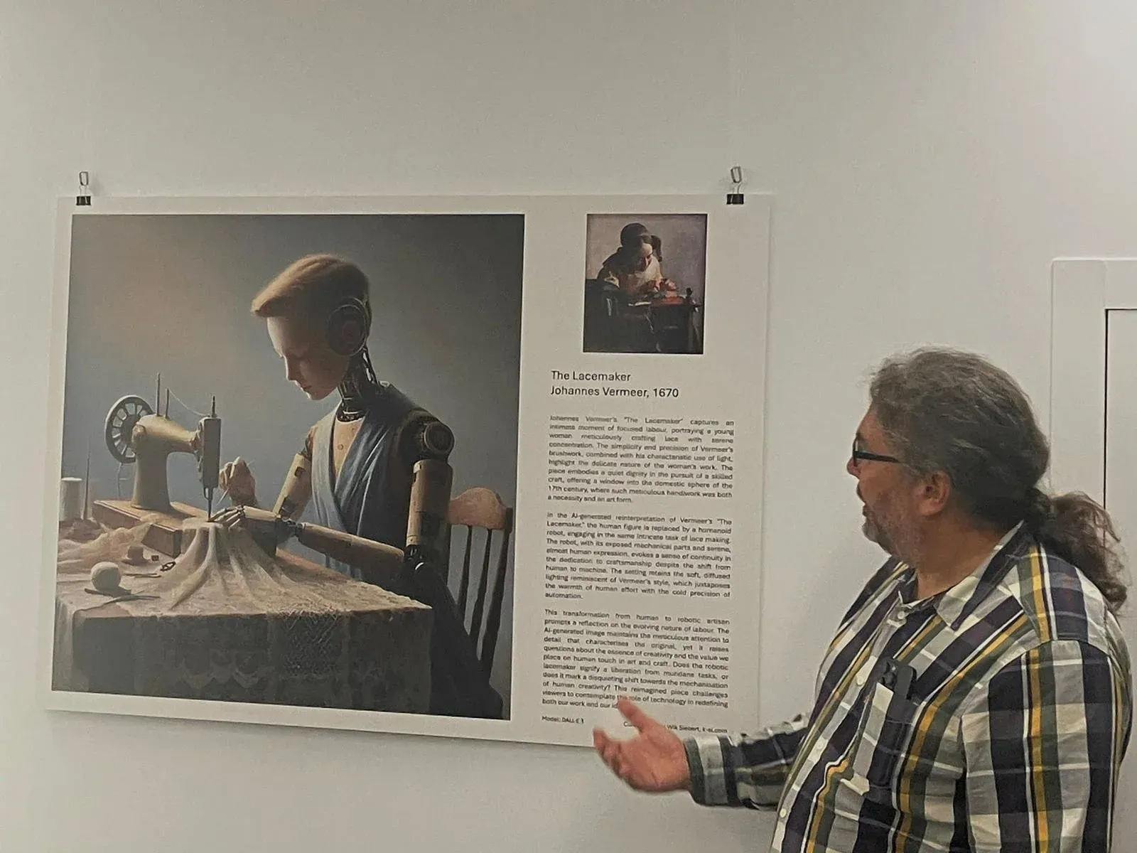 Kaj discussing the robot reimagining of The Lacemaker beside its printed exhibition poster.
